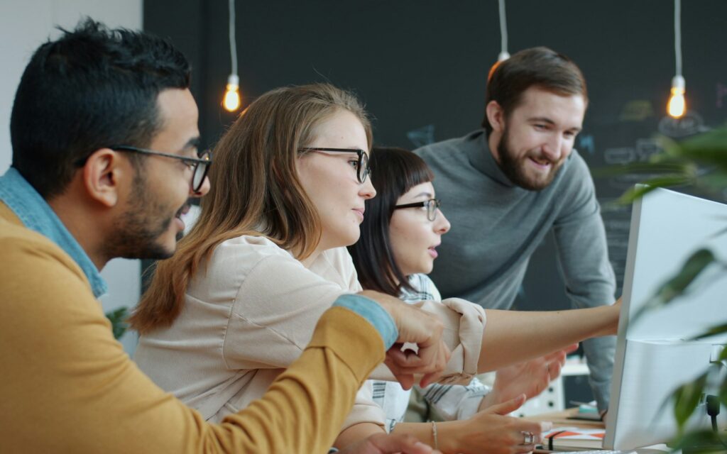 Diverse team collaborating around a computer screen