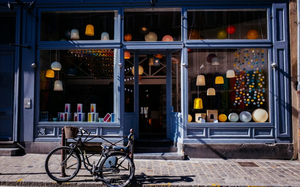 A bicycle parked on a cobblestone sidewalk in front of a lamp shop