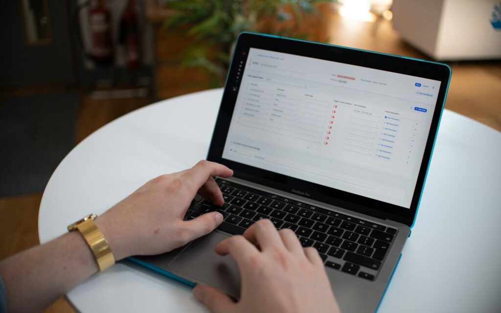 Hands typing on a laptop with a spreadsheet on screen